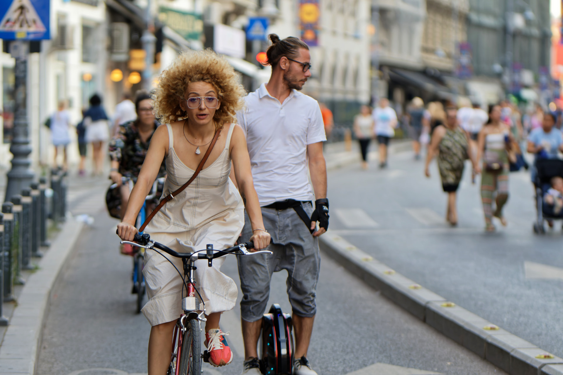 A woman riding a bicycle along a busy city street in summer