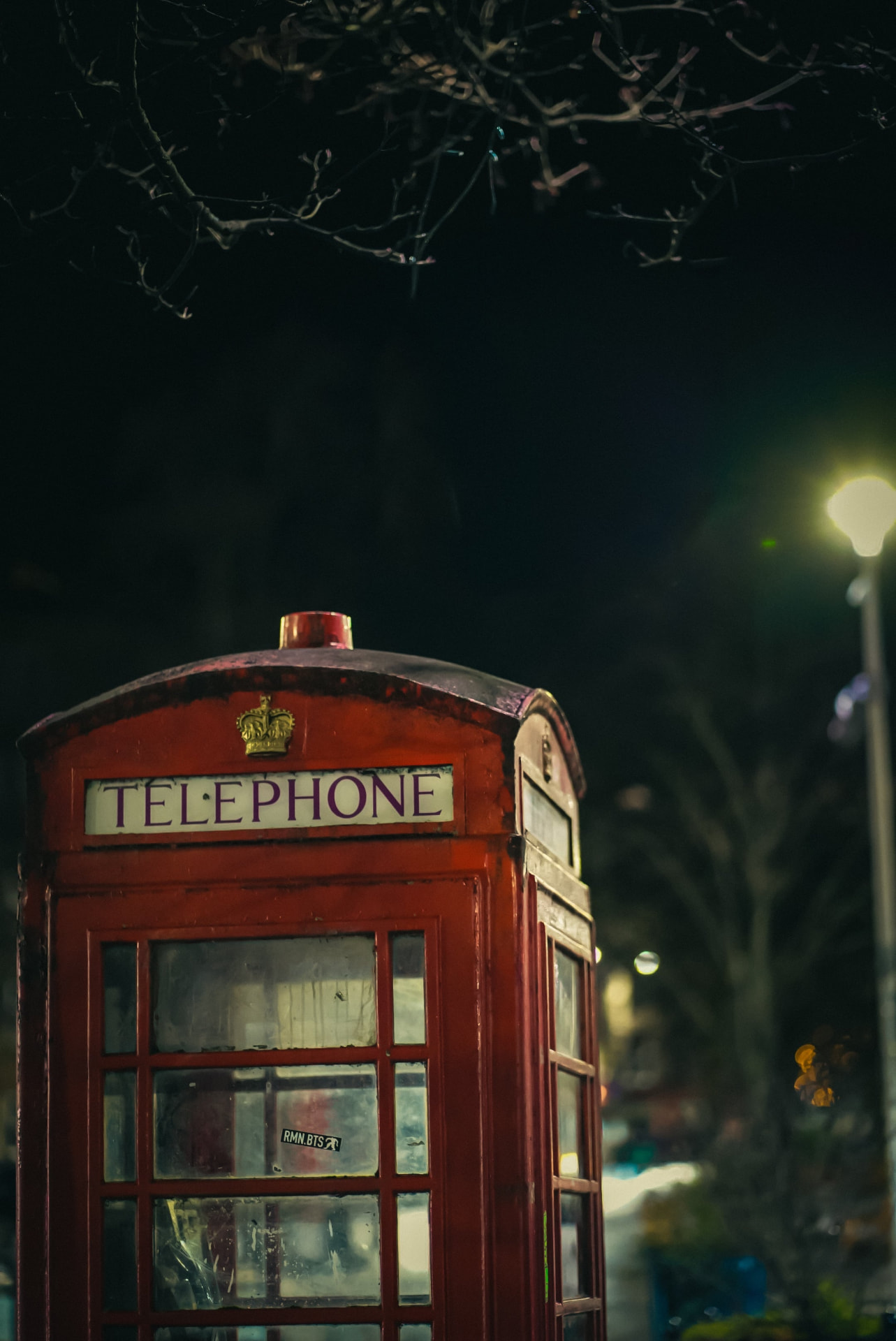 A red telephone box lit at night on a city street